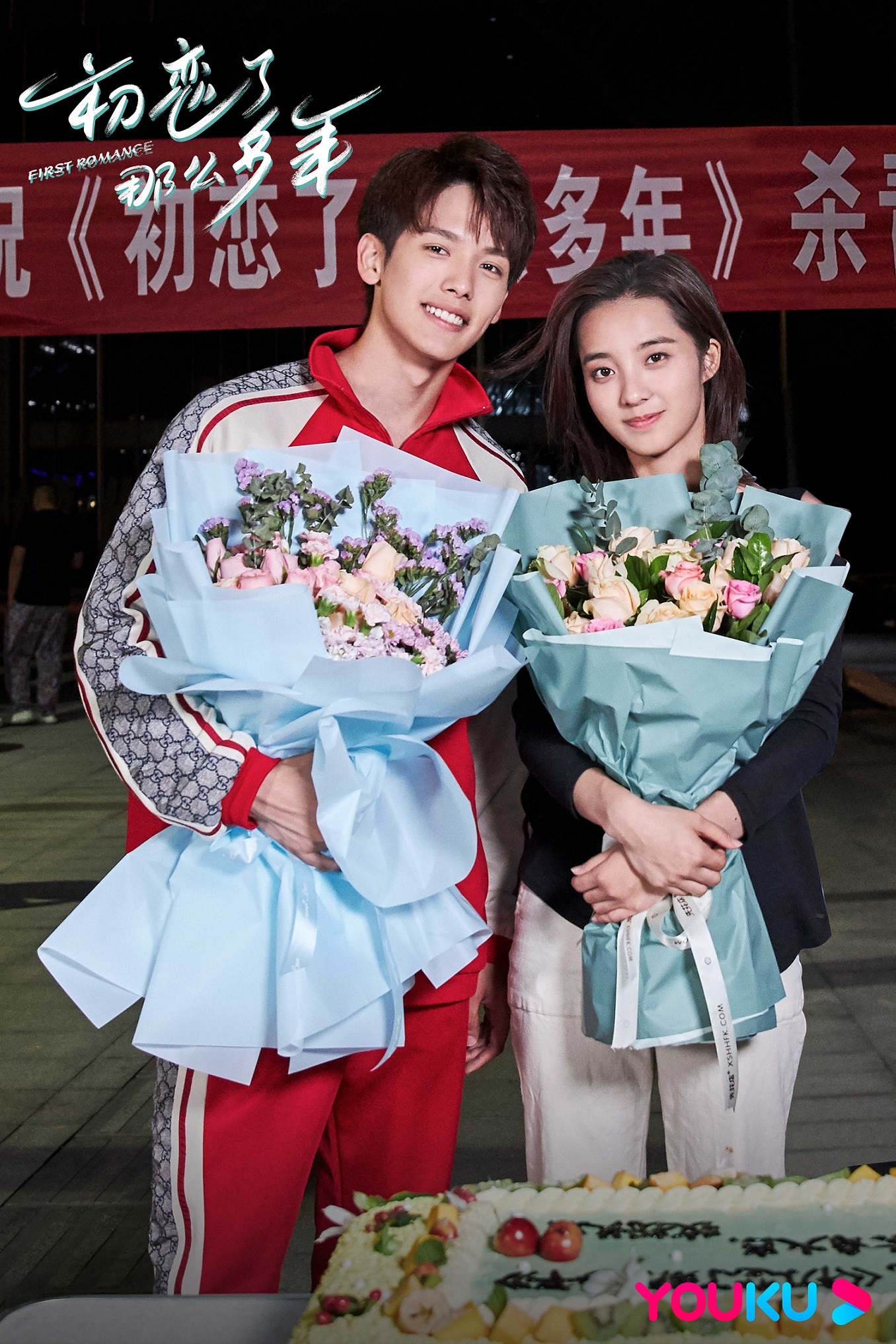 王以纶一身红色白条纹运动套装,手捧鲜花与剧组主创合影留念,庆祝